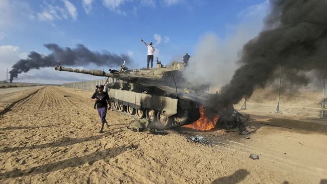 当地时间10月7日，加沙地带，巴勒斯坦人在一辆被摧毁的以色列梅卡瓦坦克旁庆祝。图/视觉中国