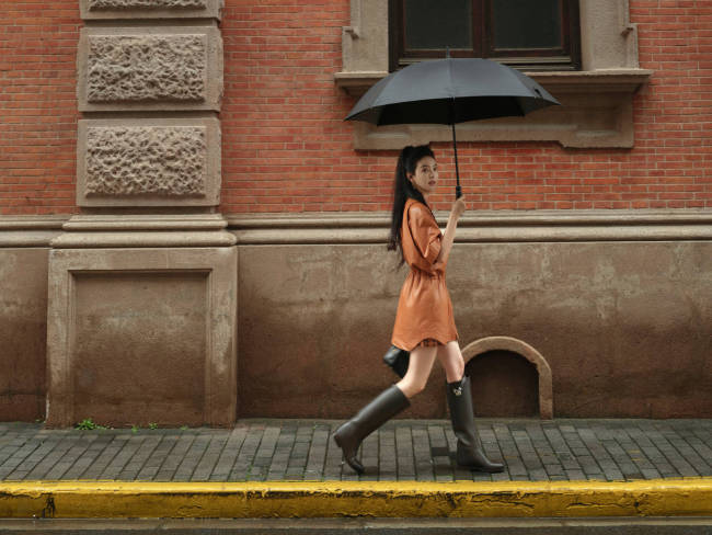 章若楠穿橘色皮裙漫步上海 手撑雨伞步伐轻盈灵动